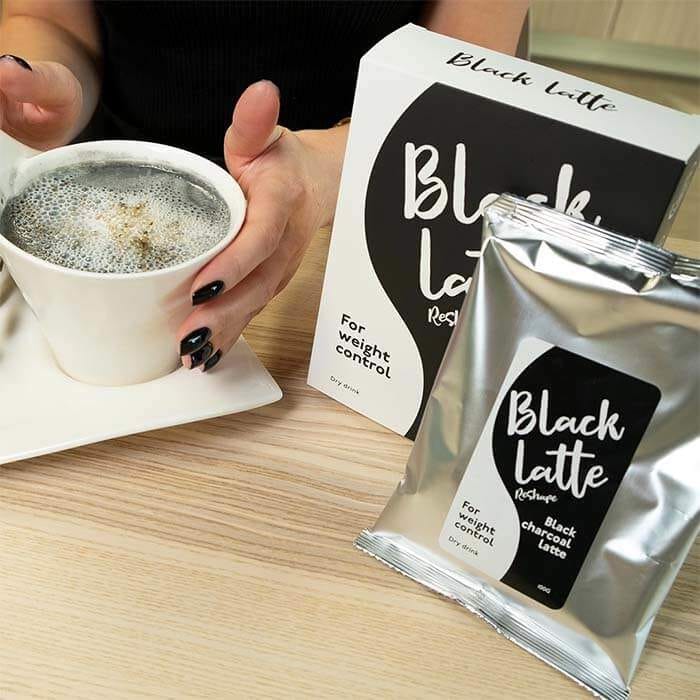 Девушка за столом пьют угольный кофе для похудения - Black Latte